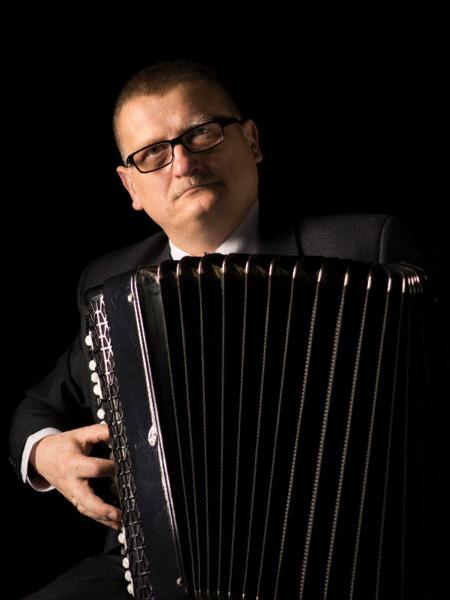 Akordeonista Jerzy Mądrawski pozuje z akordeonem guzikowym