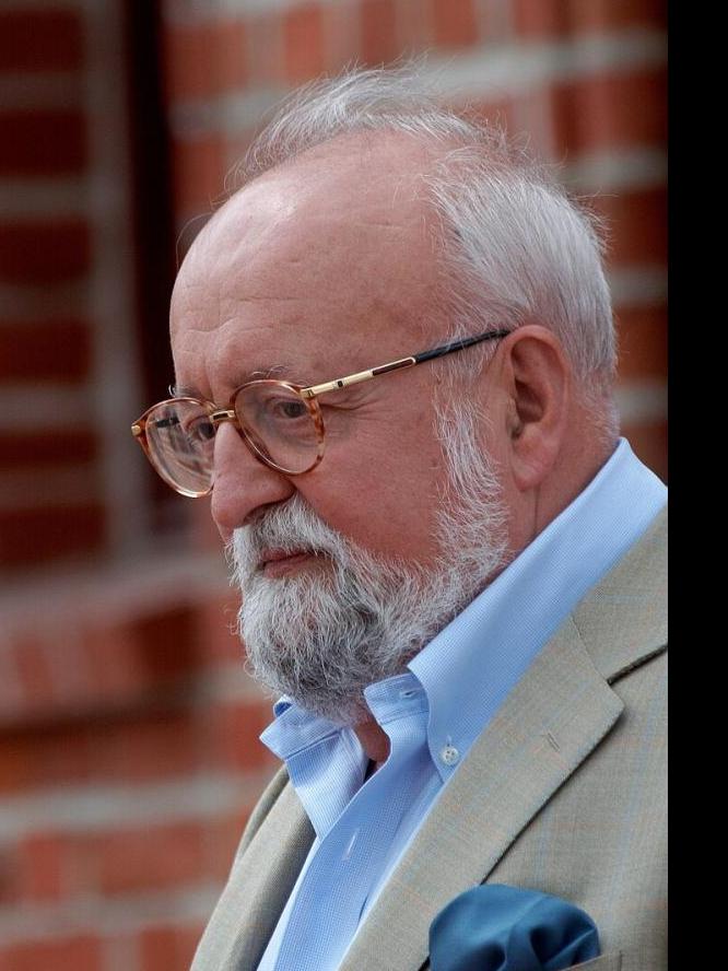 Kompozytor Krzysztof Penderecki pozuje do zdjęcia w okularach i marynarce z butonierką oraz niebieską koszulą