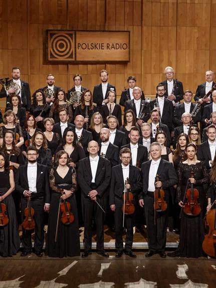 Orkiestra Polskiego Radia, muzycy ubrani w czarne sukienk i fraki stoją w czterech rzędach na estradzie 
